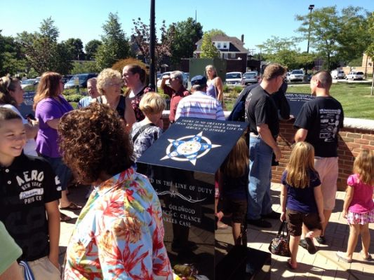 Visitors gathered around the memorial monument inscribed "In the line of duty"